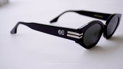 Black sunglasses with a Engraved logo on a light gray background